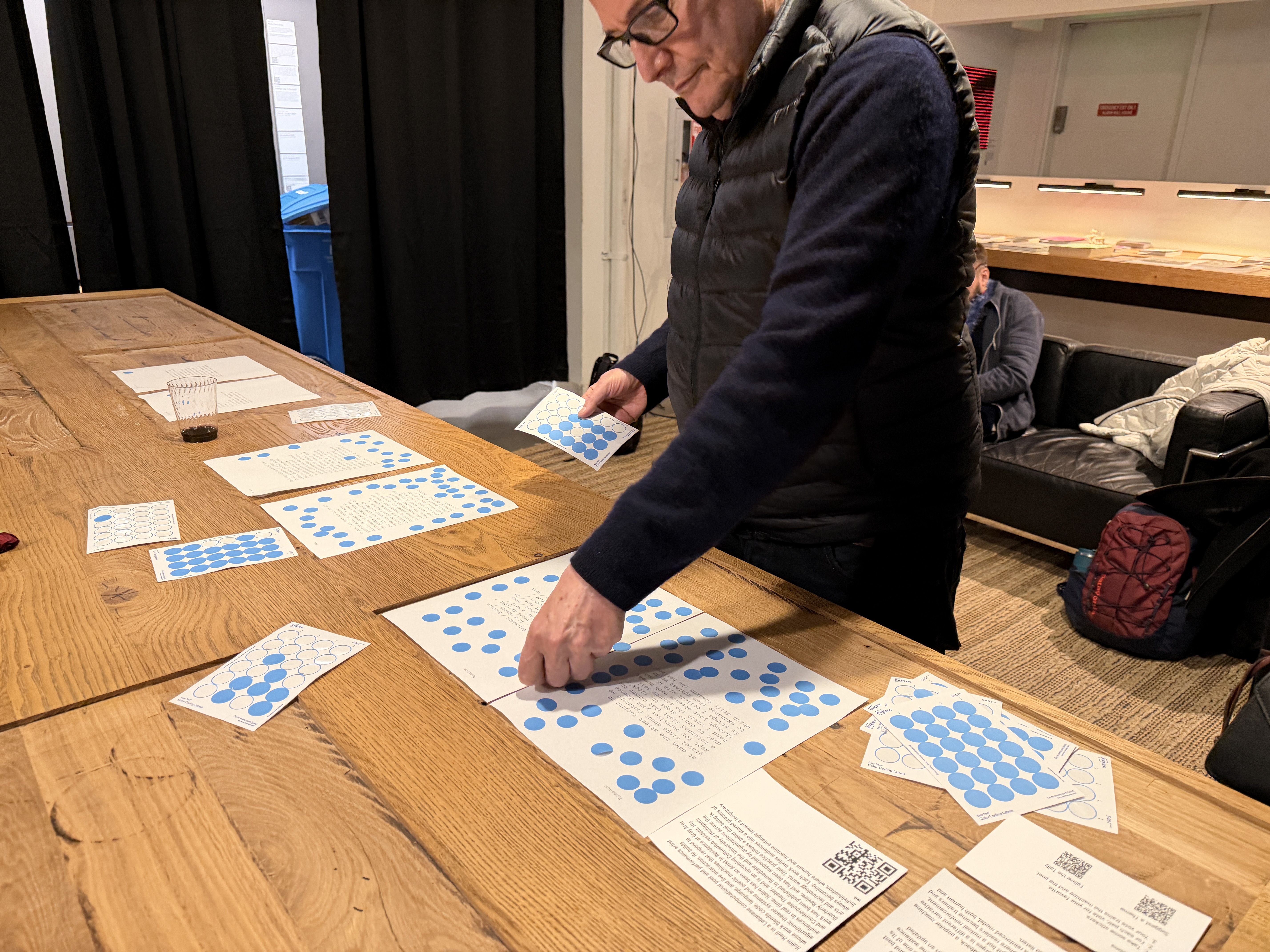 Audience member placing blue voting stickers on printed poems