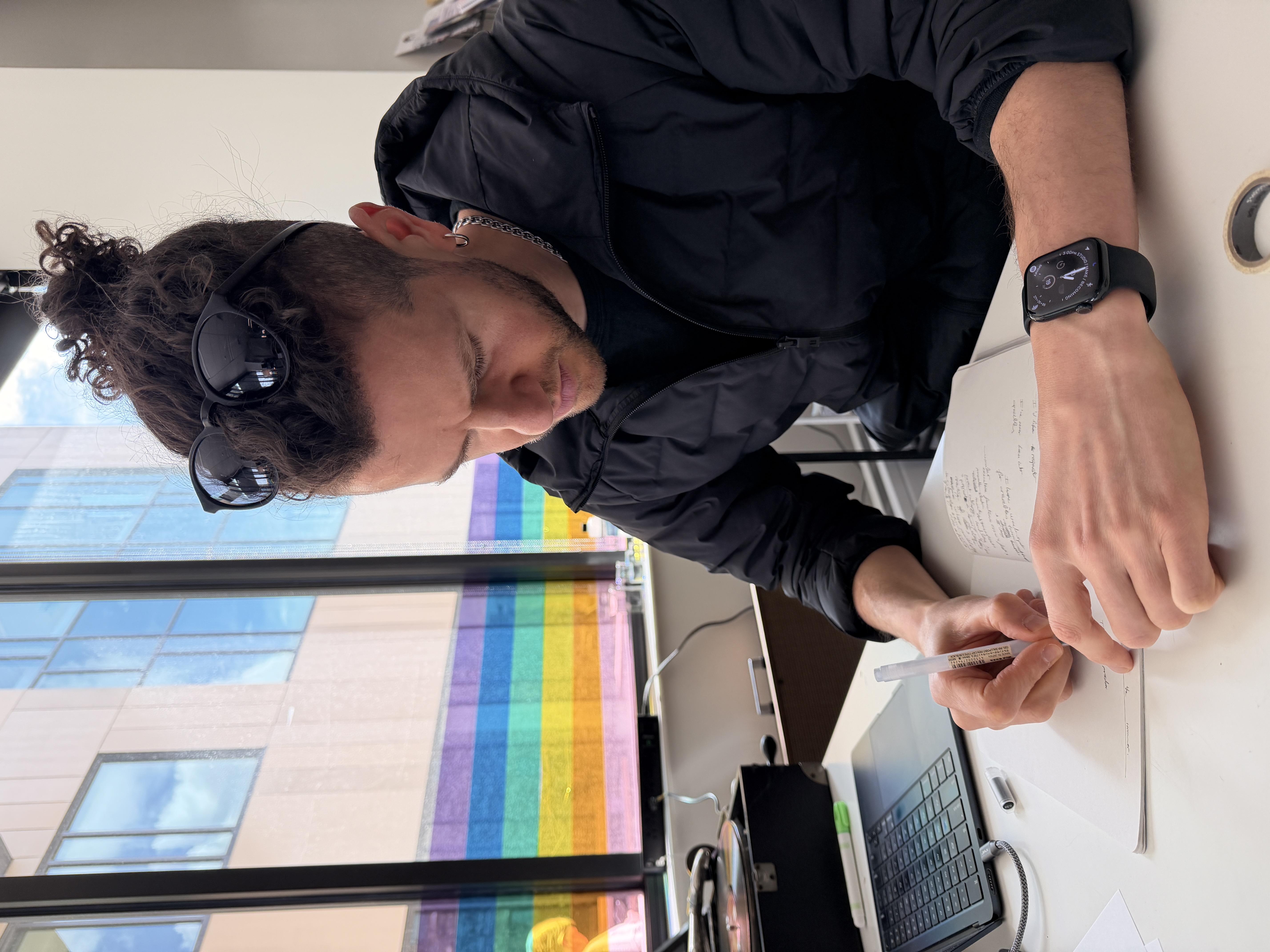 The poet writing with a rainbow flag and lab equipment in the background